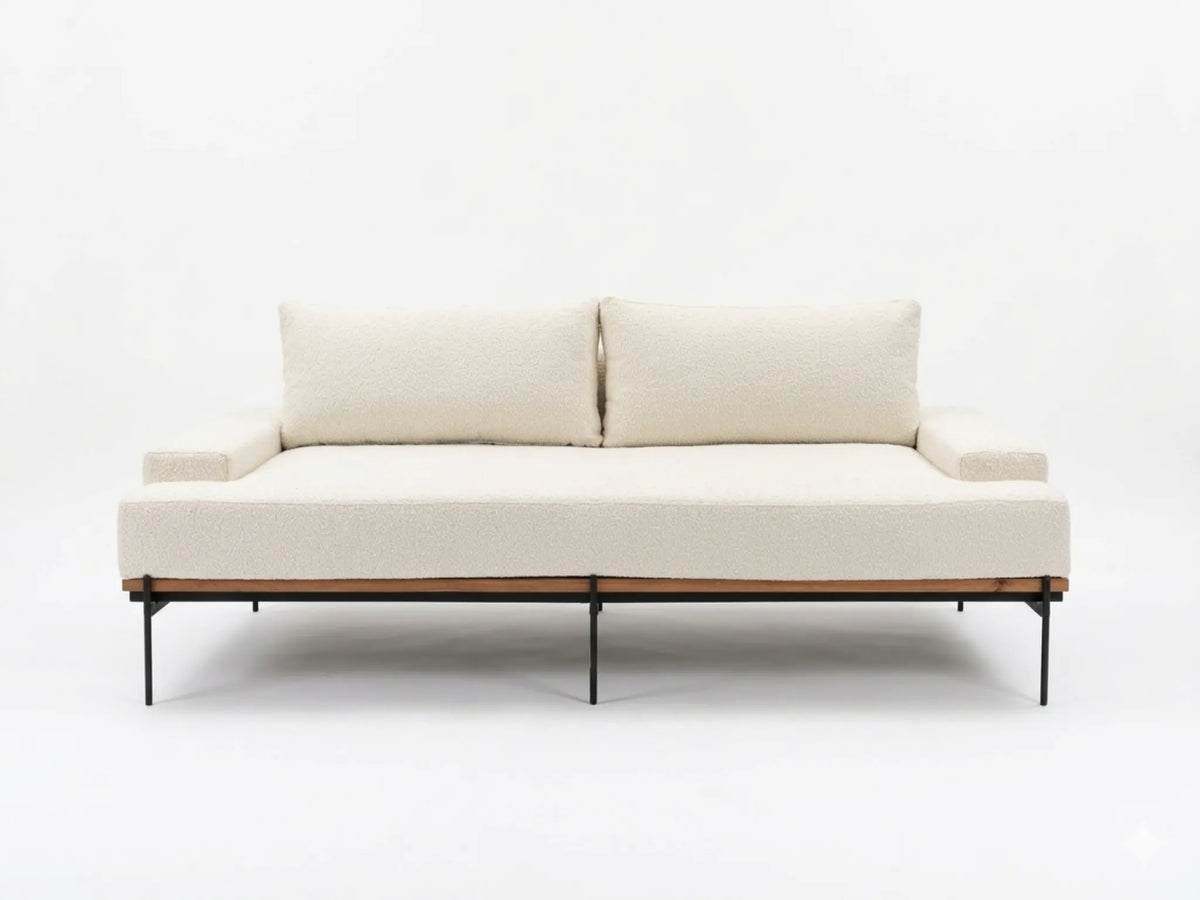 A modern low-profile daybed or sofa with off-white textured upholstery, two back cushions, a light wood frame, and slim black metal legs, shown against a plain white studio background.