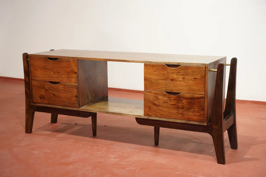 Mid-century modern wooden console table with two drawers on each side, an open center shelf, and a light wood top and lower shelf, shown on a terracotta-colored floor against a white wall.
