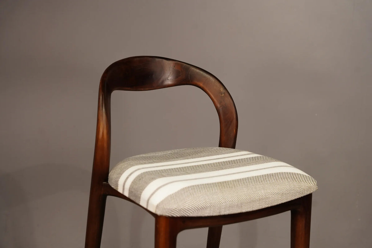 A wooden chair with a curved backrest and a striped upholstered seat cushion in beige and white, shown against a plain gray background.
