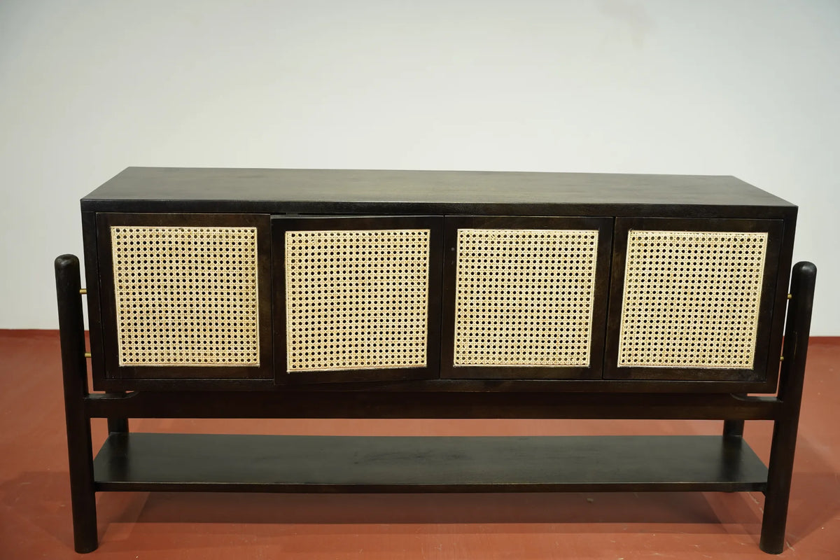 A dark wood sideboard cabinet with four cane or rattan door panels and a lower shelf, photographed against a plain light wall and reddish-brown floor.