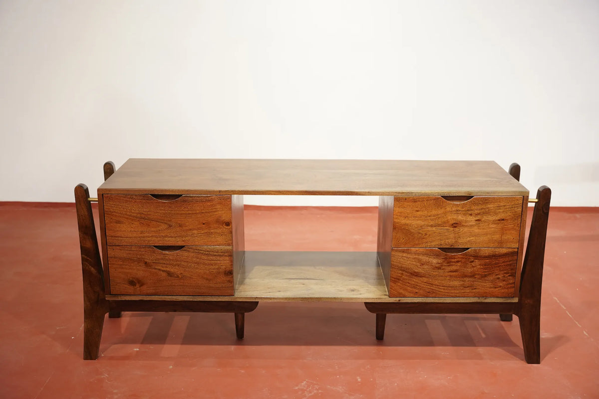 A mid-century modern wooden console table with a warm brown wood finish, featuring two drawers on each side and an open center shelf, set against a plain white wall and reddish-brown floor.