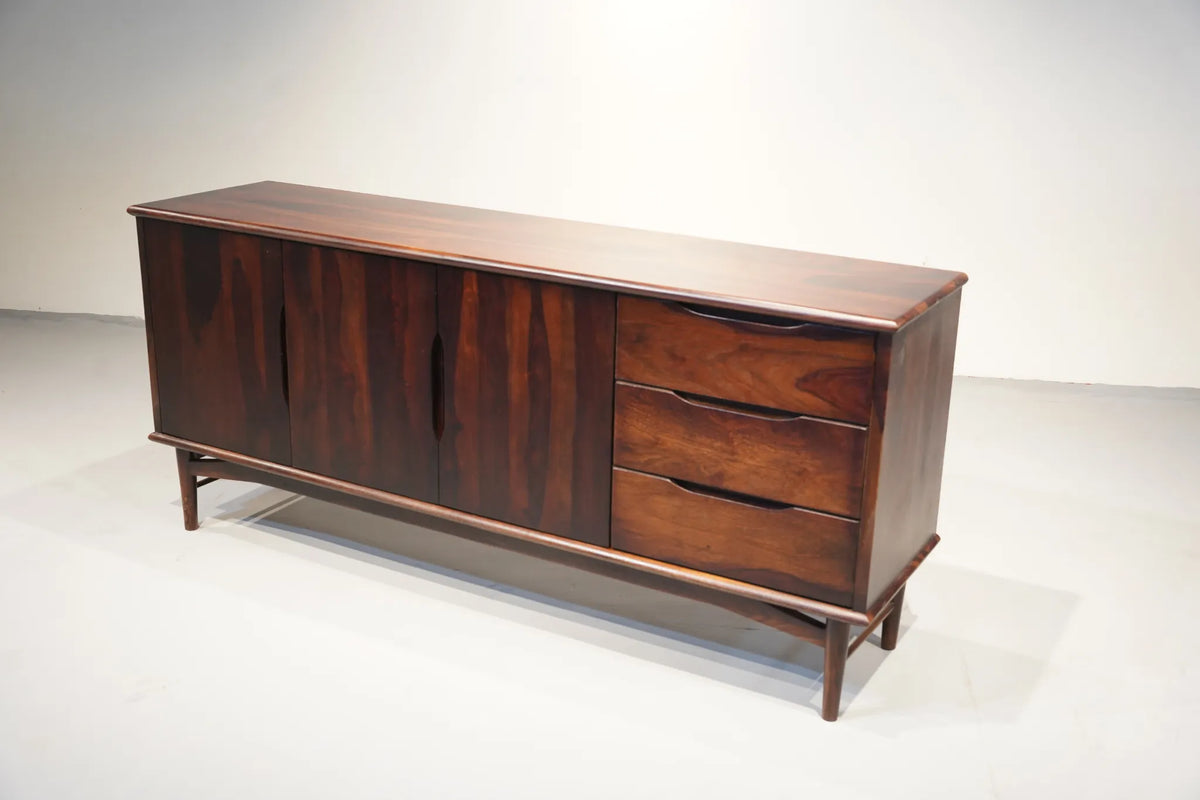 Mid-century modern wooden sideboard with three cabinet doors and three drawers on the right, finished in dark reddish-brown wood grain, photographed in a studio setting.