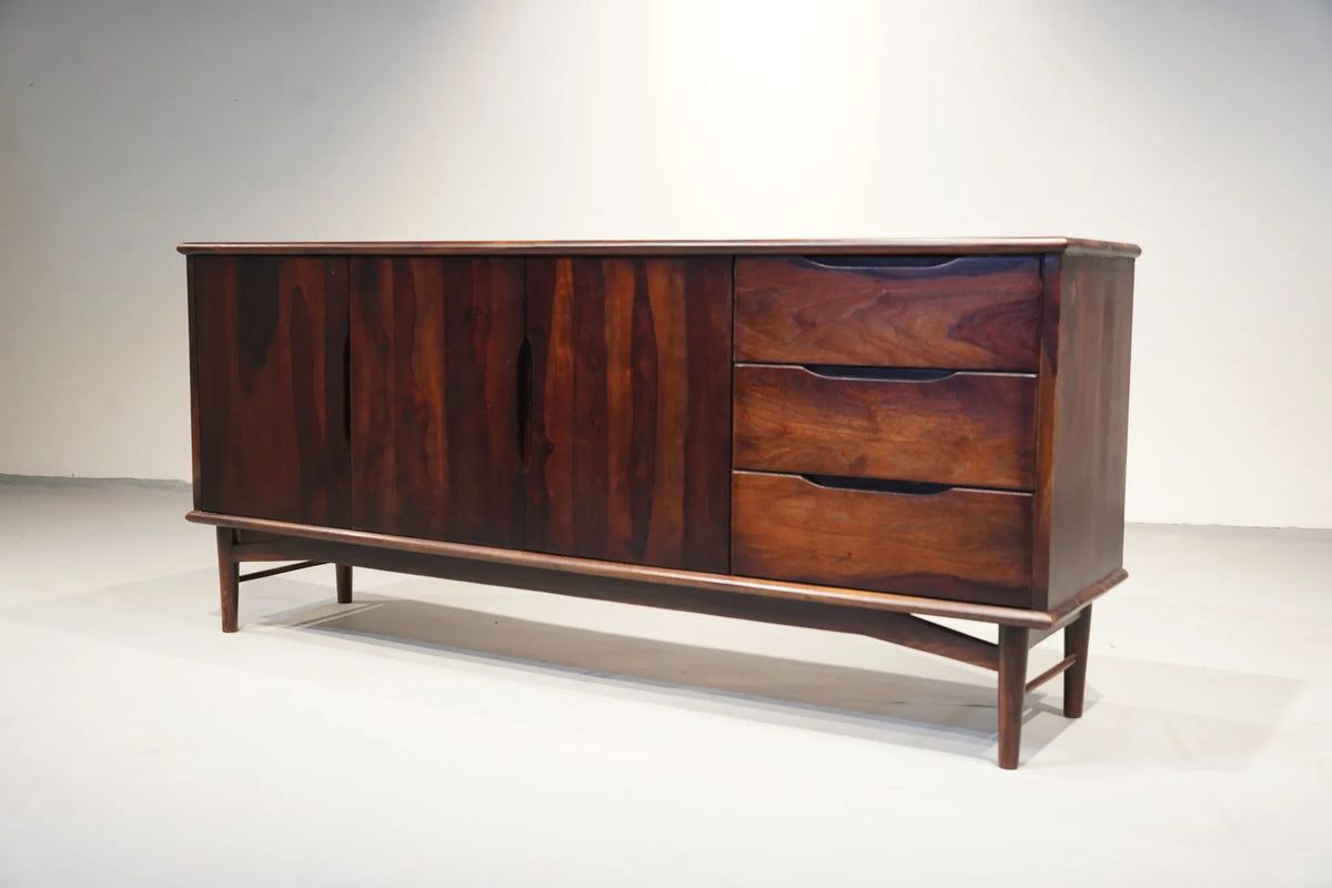 Mid-century modern wooden sideboard with a dark rosewood finish, featuring three cabinet doors on the left and three drawers on the right, supported by angled legs.
