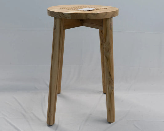 A light natural wood stool with a round woven cane seat and three tapered legs, photographed against a white fabric backdrop.
